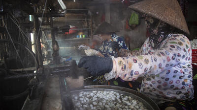 Trong những xưởng kéo tơ, những người thợ miệt mài làm việc trong màn khói bốc nghi ngút từ nồi nước luộc kén.